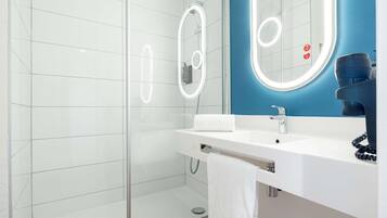 Een moderne badkamer met een douchecabine van glas, een witte wastafel met spiegel en een blauwe accentmuur.