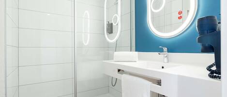 A modern bathroom with a glass-enclosed shower, a white sink with a mirror, and a blue accent wall.