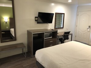 A hotel room with a bed, a desk with a computer, a TV, a microwave, and a door. - Gilroy Inn (Gilroy)