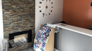 Zona de recepción con pared de piedra, un reloj y una selección de revistas.