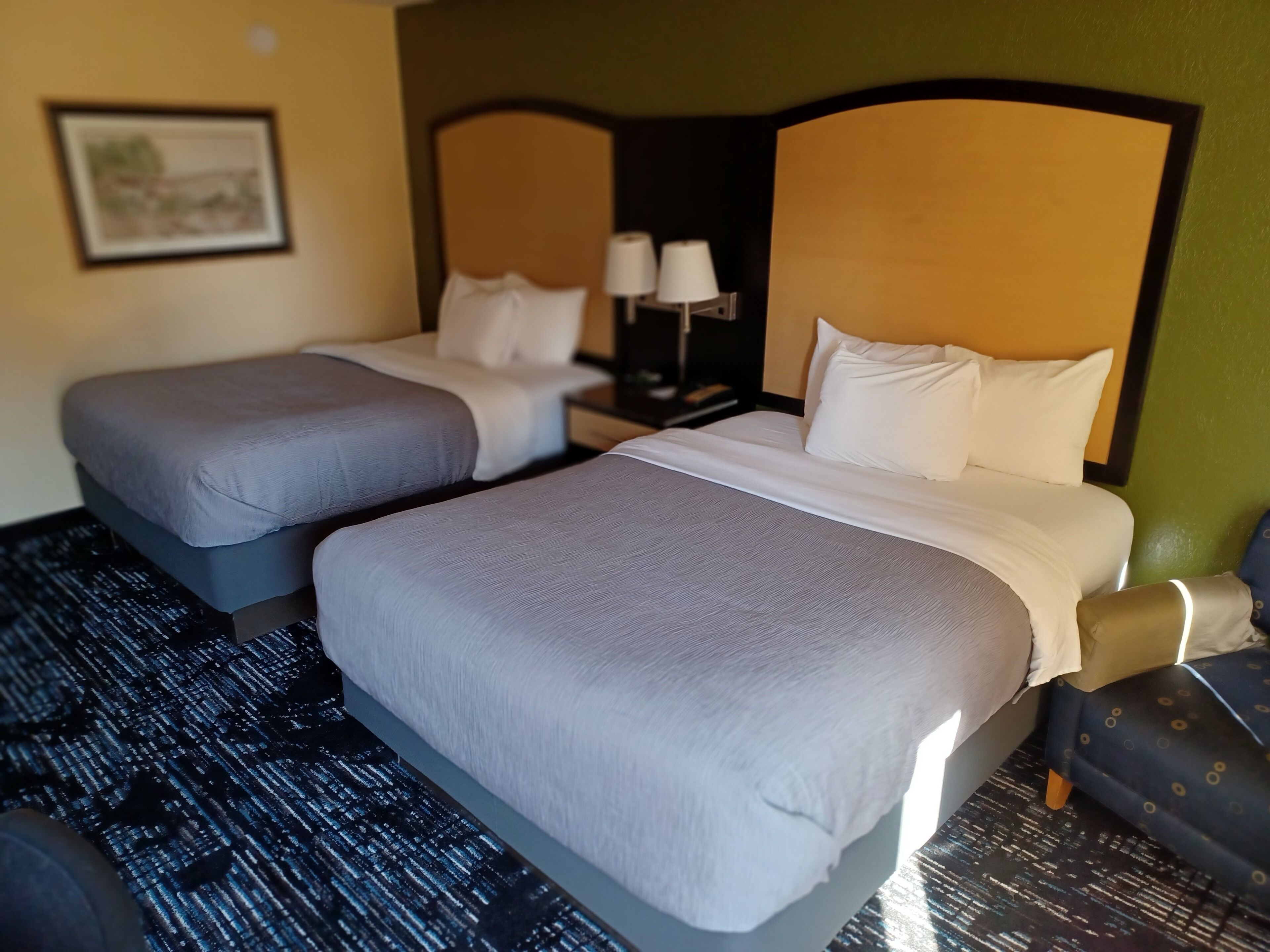 Ein Hotelzimmer mit zwei Betten, einem Nachttisch mit Lampen und einem Sessel.