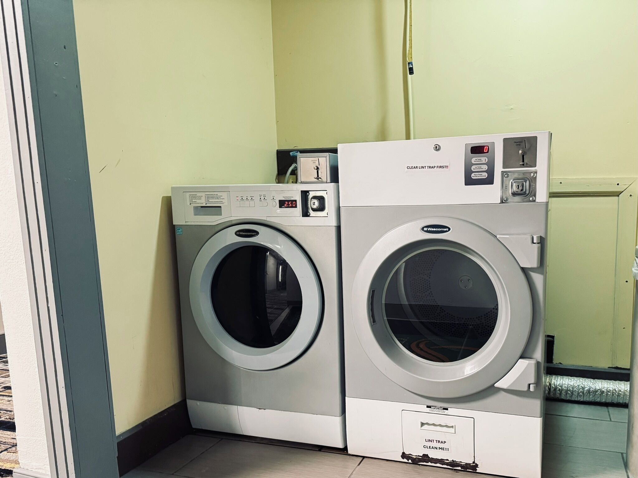 Two front-loading washing machines in a laundry room with a tiled floor and a door in the background.