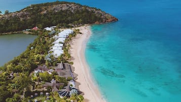 A resort with a beach, a pool, and a mountain in the background.