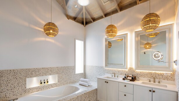 A modern bathroom with a freestanding bathtub, white cabinetry, and a large mirror above the sink.