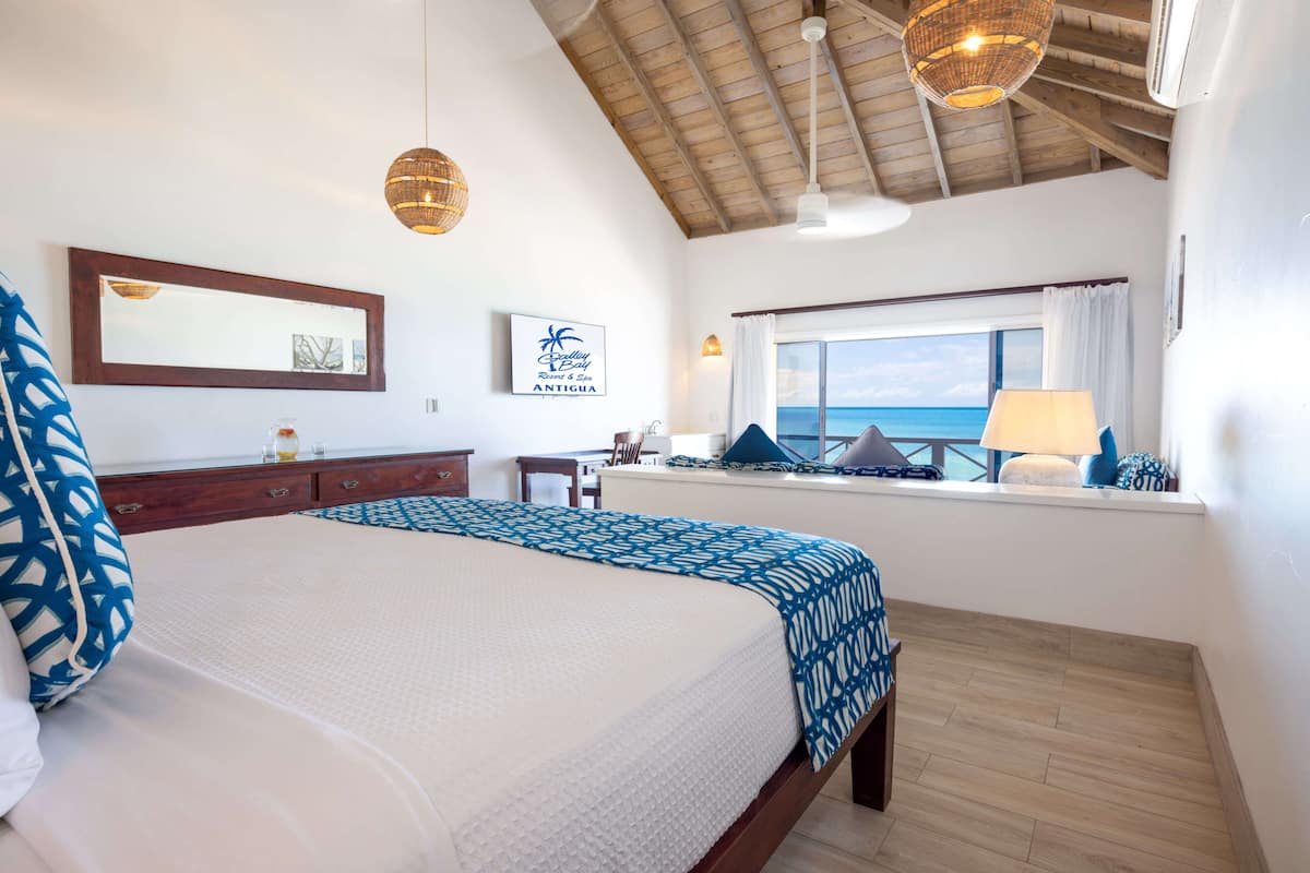 A bedroom with a bed, a dresser, a window with a view, and a ceiling fan.