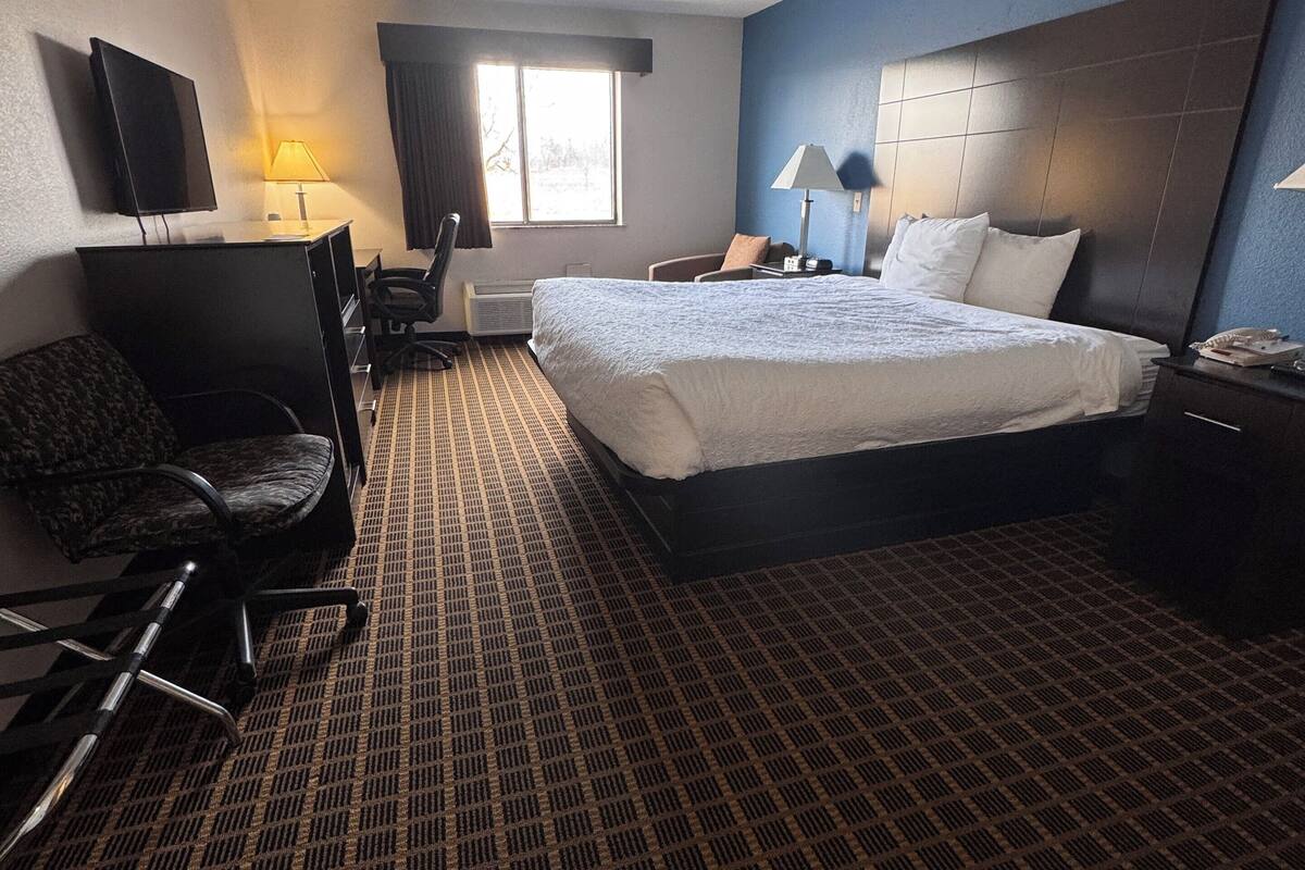 Een hotelkamer met een bed, een bureau, een stoel, een televisie en een raam.