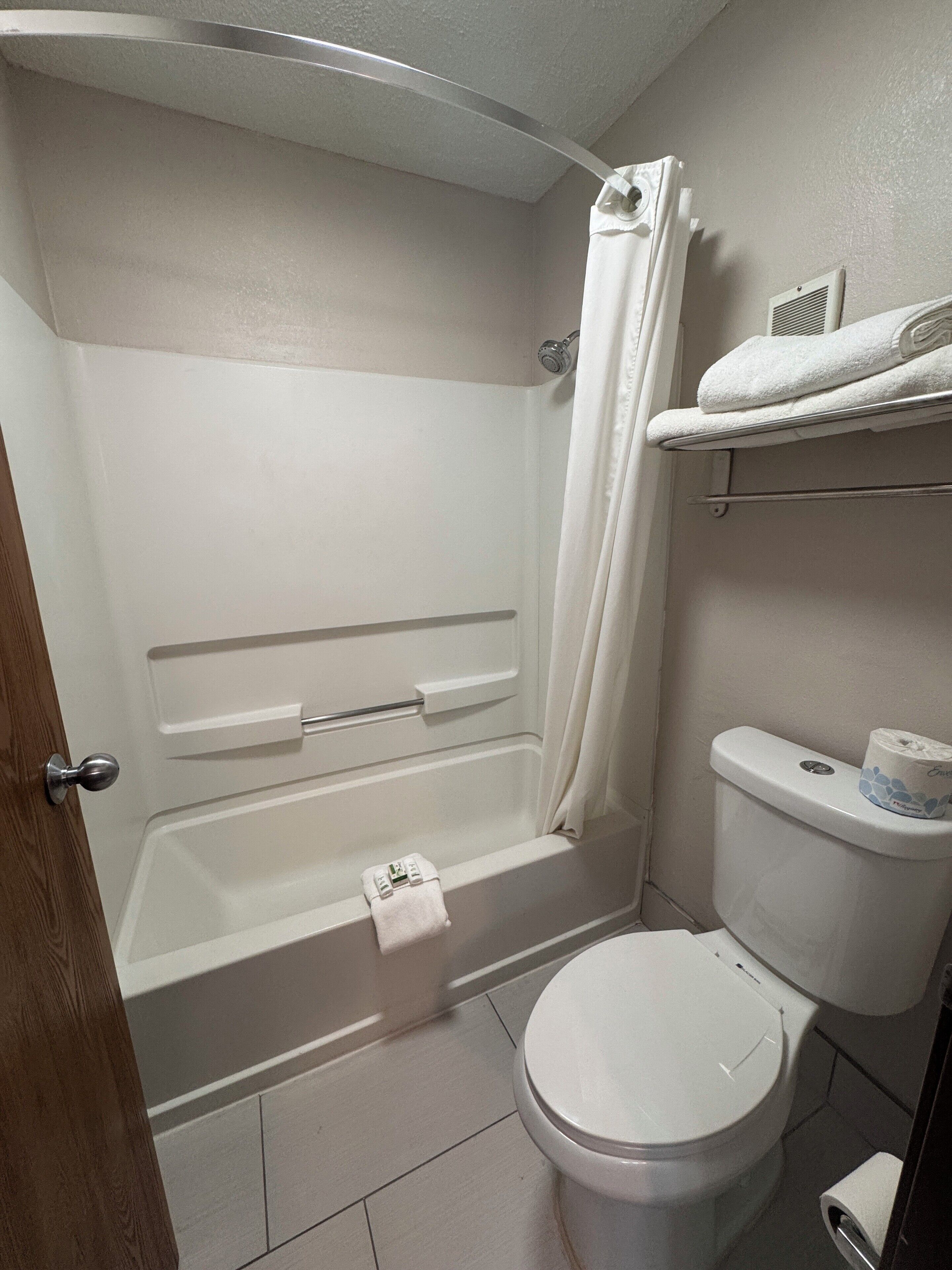 Un baño con bañera, inodoro y un perchero para toallas.