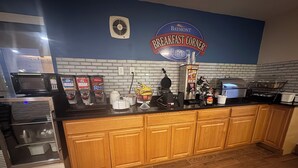 Una cocina con barra americana, microondas, tostadora y cafetera.