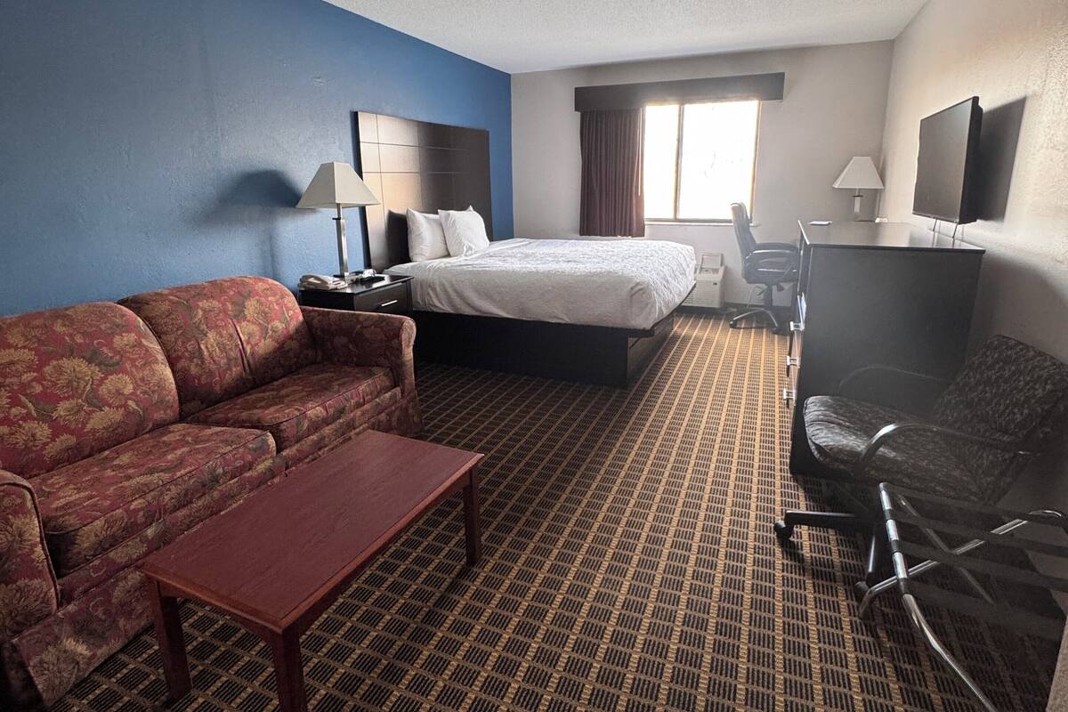 Een hotelkamer met een bed, een slaapbank, een bureau en een stoel.