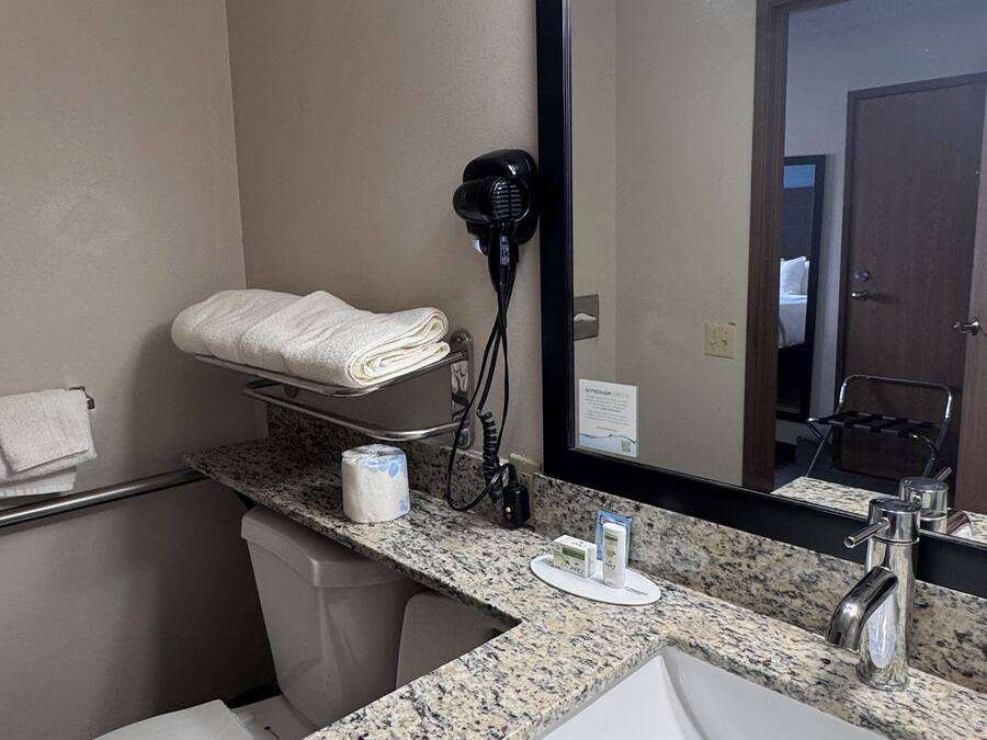 A bathroom with a sink, mirror, towel rack, and hair dryer.