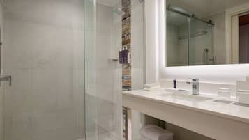 Een moderne badkamer met een douchecabine van glas, een witte wastafel met spiegel en een handdoekrek.