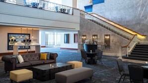 A spacious lobby with a high ceiling, a staircase, and seating areas. - Renaissance Concourse Atlanta Airport Hotel (Atlanta)