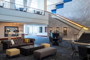 A spacious lobby with a high ceiling, a staircase, and seating areas.