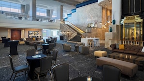 A spacious lobby with a central staircase, seating areas, and a bar. - Renaissance Concourse Atlanta Airport Hotel (Atlanta)
