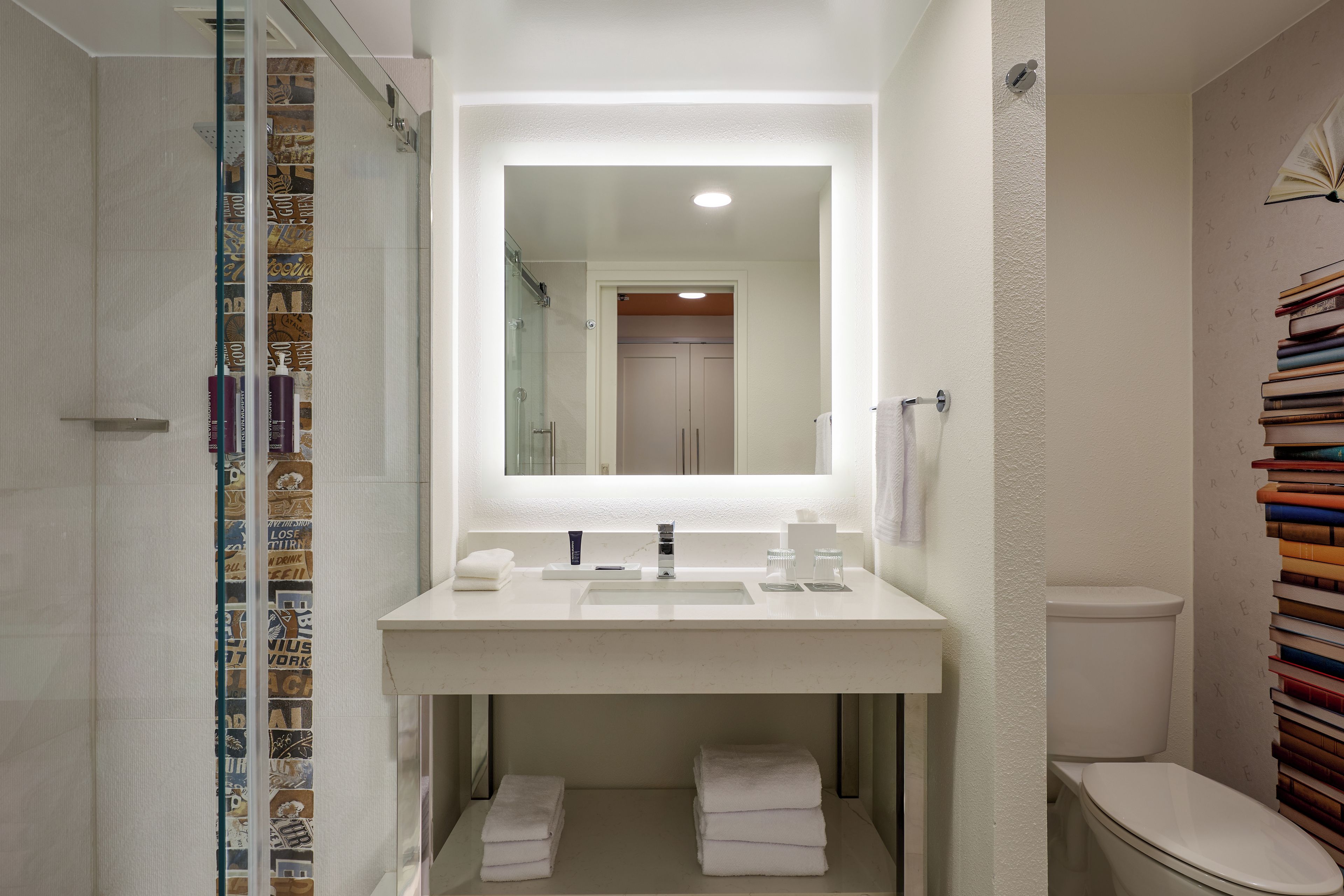 A bathroom with a white sink, mirror, and a glass shower enclosure.