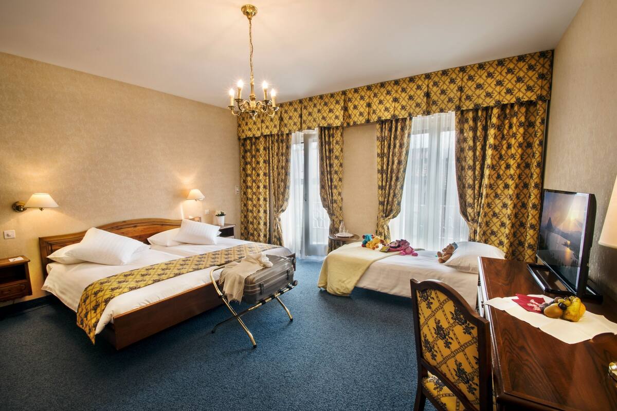 Une chambre d’hôtel avec deux lits, un bureau, une télévision et un lustre.