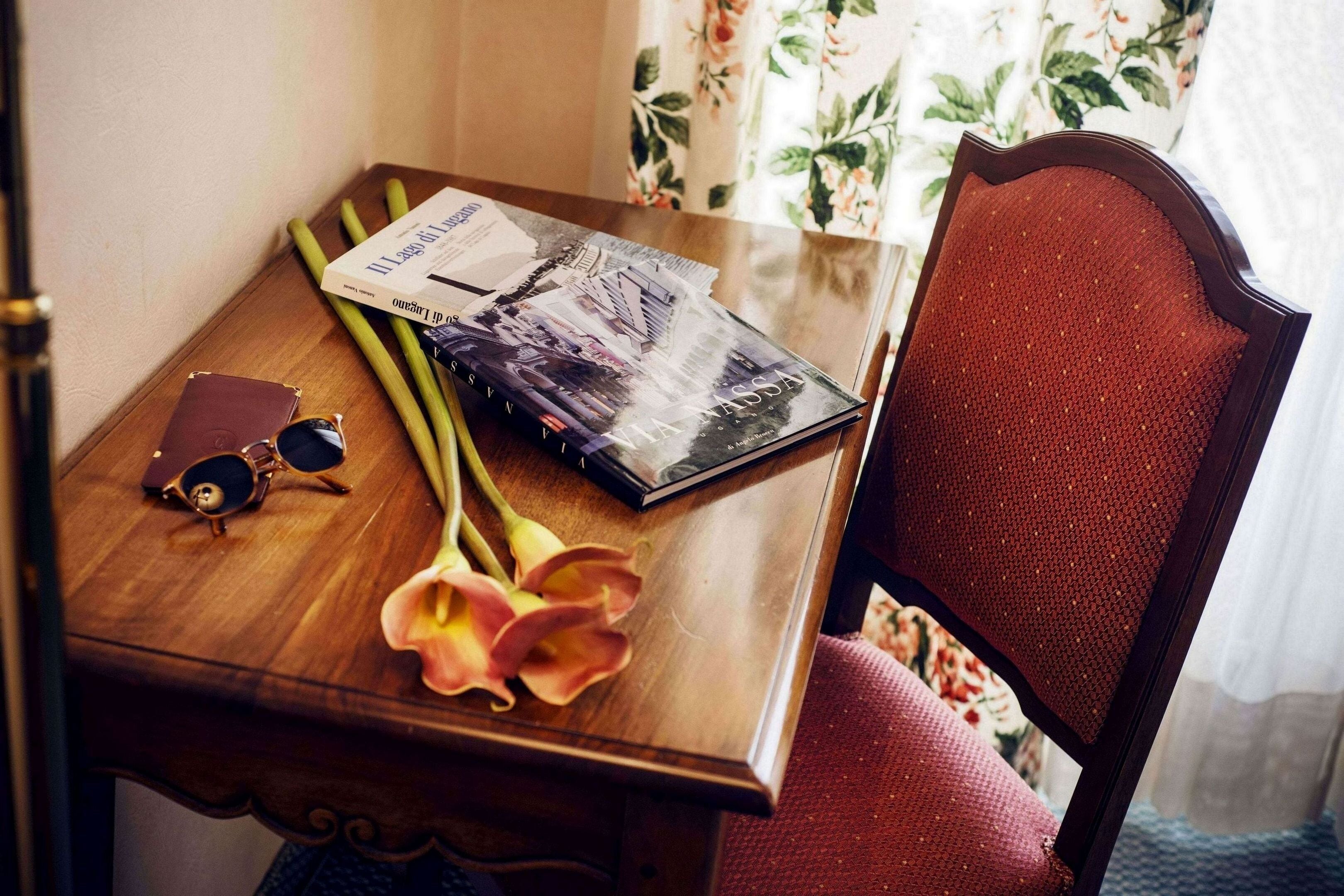 A wooden table with a book, sunglasses, and a bouquet of flowers.