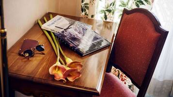 Een houten tafel met een boek, een zonnebril en een bloemenboeket.