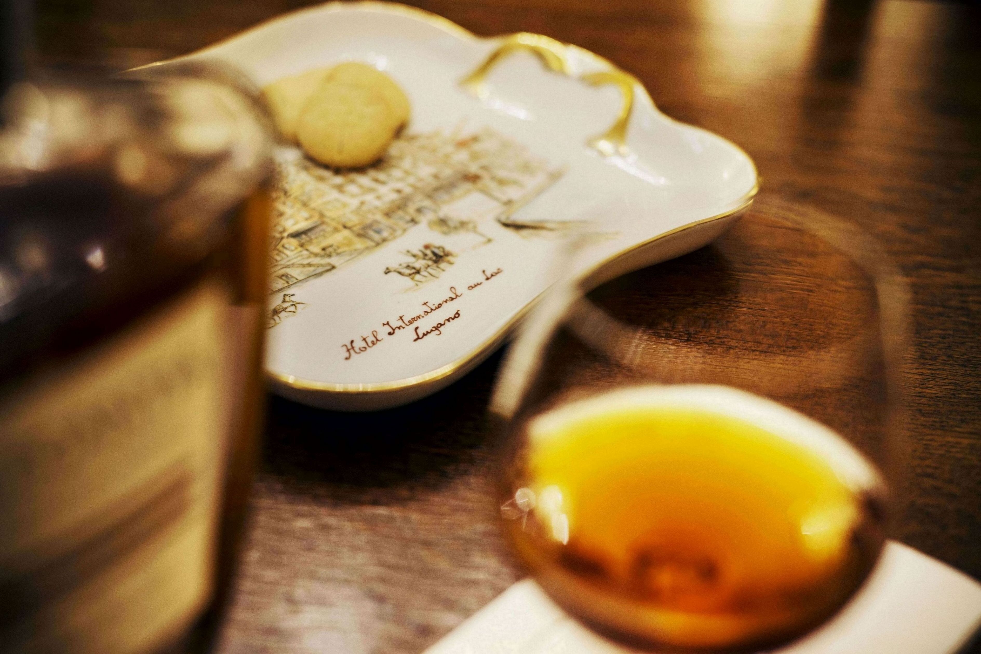 A table with a decorative plate, a bottle, and a glass of amber liquid.