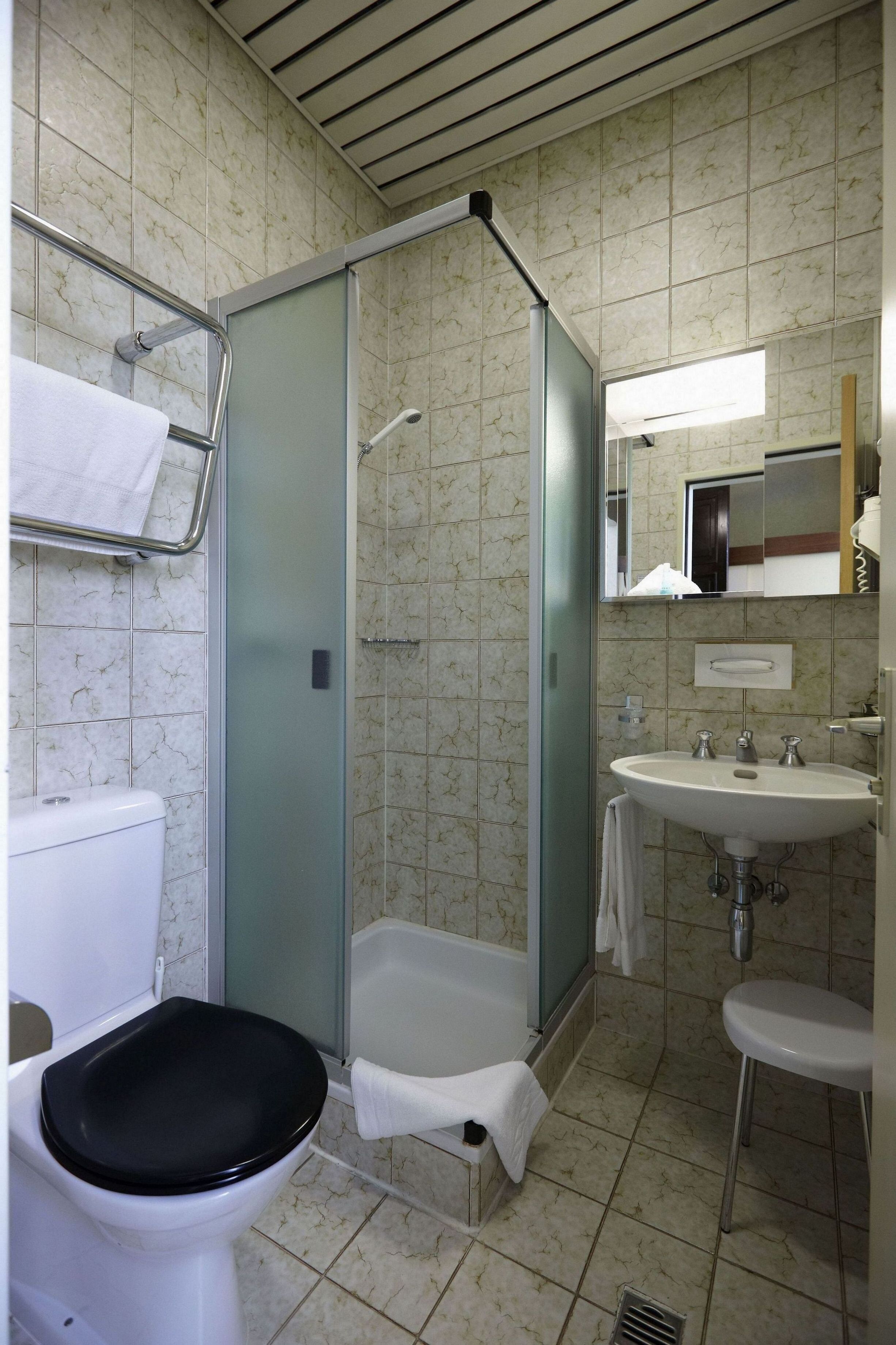 Un baño con inodoro, cabina de ducha, lavabo y espejo.