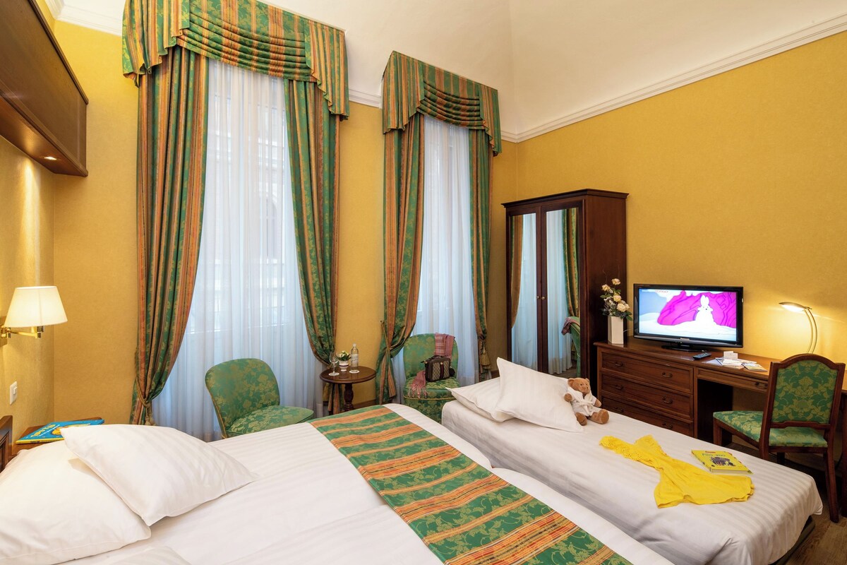 A hotel room with two beds, a television, a desk, and a chair.
