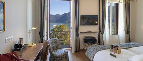 Une chambre d’hôtel avec un bureau en bois, deux chaises, un lit, une télévision et une vue sur les montagnes.