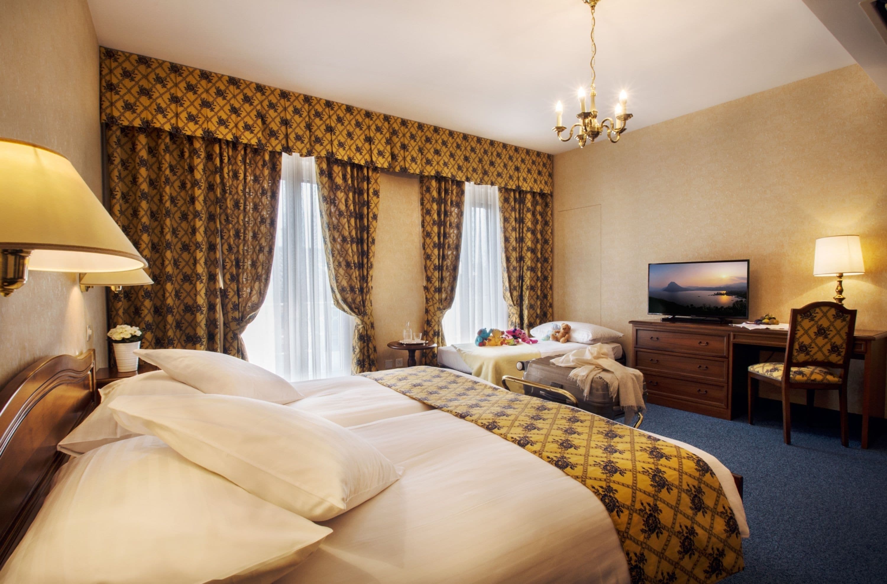 Habitación de hotel con dos camas, un escritorio, un televisor y una silla.