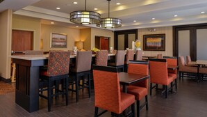 A hotel dining area with multiple tables and chairs, a bar, and artwork on the walls. - Hampton Inn Idaho Falls/Airport (Idaho Falls)