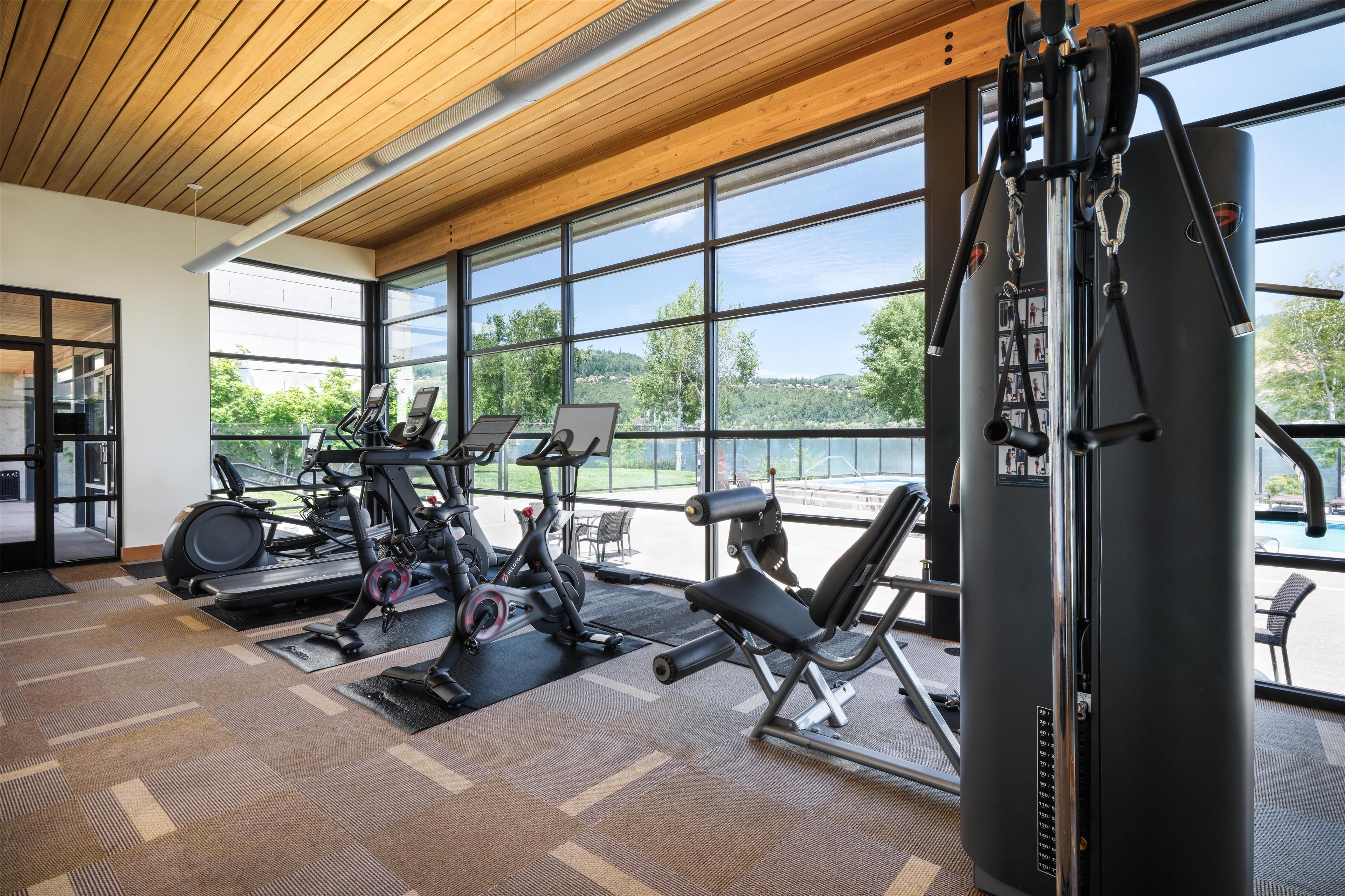 A gym with exercise equipment, large windows, and a view of a lake.