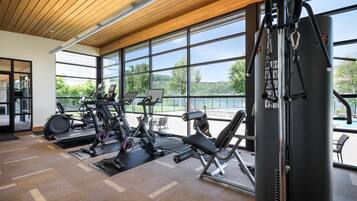 A gym with exercise equipment, large windows, and a view of a lake.