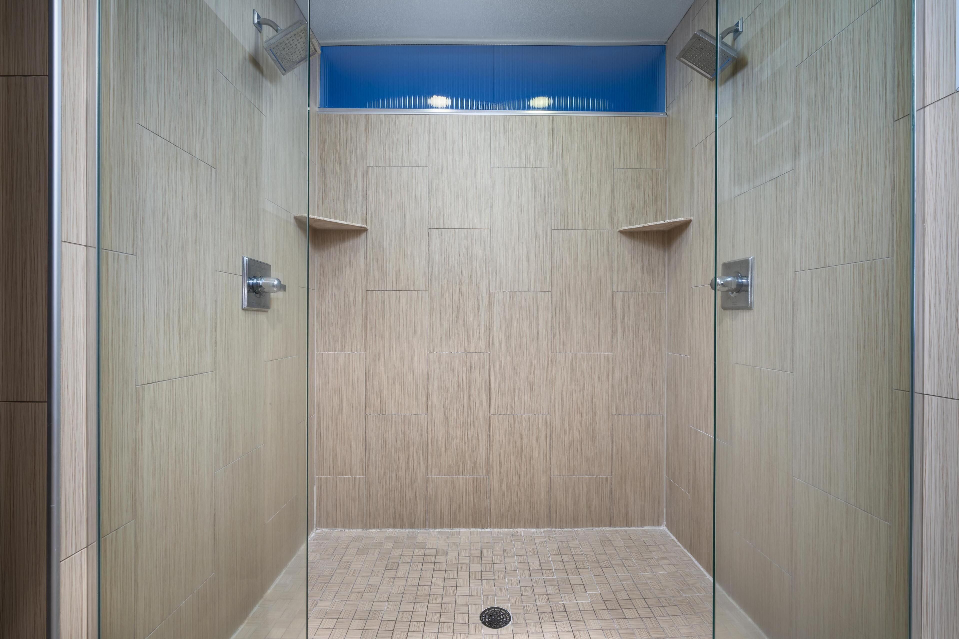A walk-in shower with a tiled floor and wooden walls.
