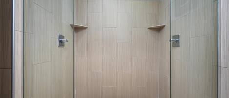 A walk-in shower with a tiled floor and wooden walls.