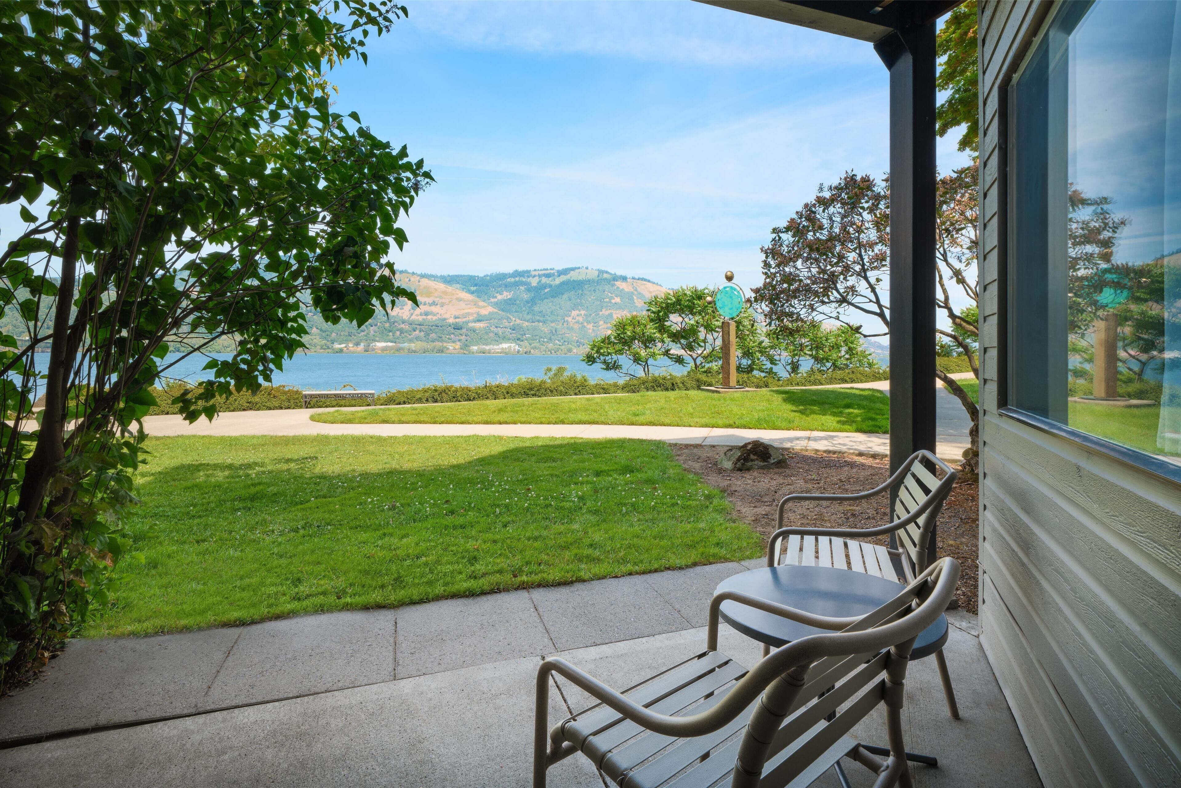 A patio with outdoor seating overlooking a lake and hills.
