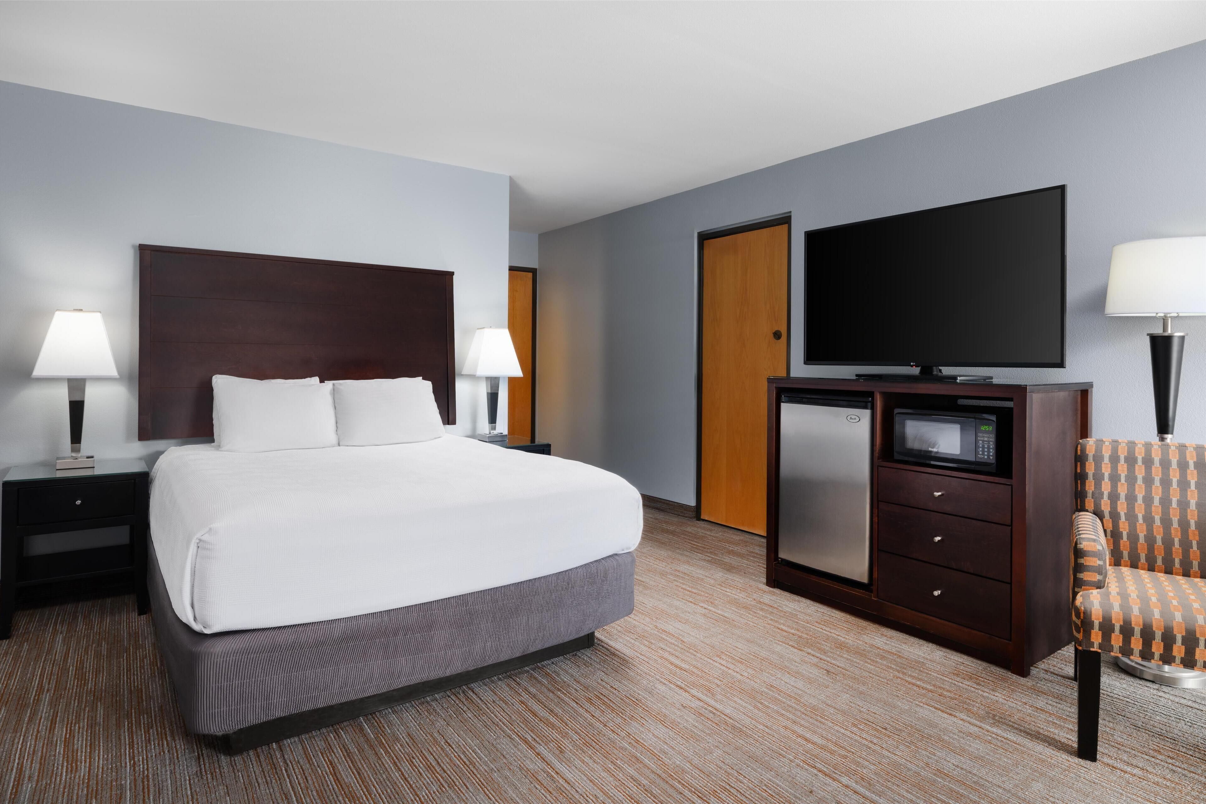 Une chambre d’hôtel avec un grand lit, une télévision, un four à micro-ondes, un bureau et une chaise.