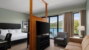 Une chambre d’hôtel équipée d’un lit, d’une télévision, d’un bureau, d’une chaise, d’un canapé et offrant une vue sur un lac.
