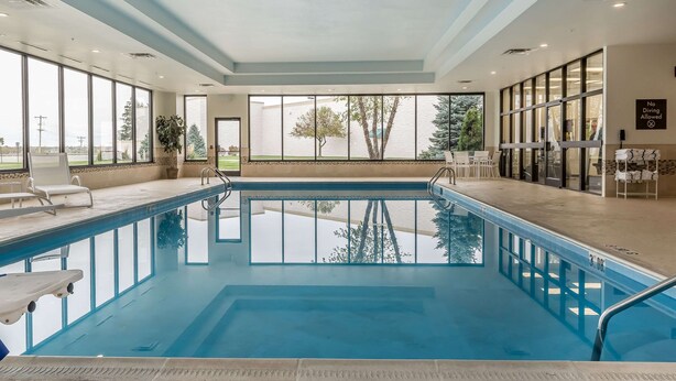 Piscina interior com paredes de vidro transparente, plataforma de mergulho e aviso indicando que mergulhos não são permitidos.