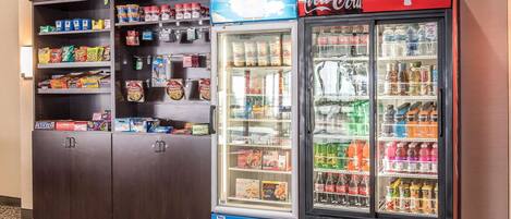 Máquina expendedora llena de aperitivos y un refrigerador Coca-Cola con diversas bebidas.