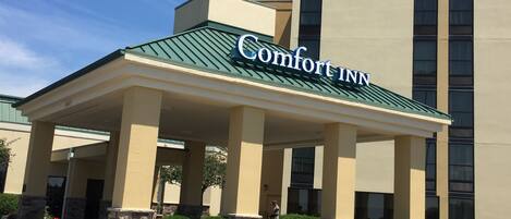A Comfort Inn hotel with a covered entrance, stone pillars, and a green roof.