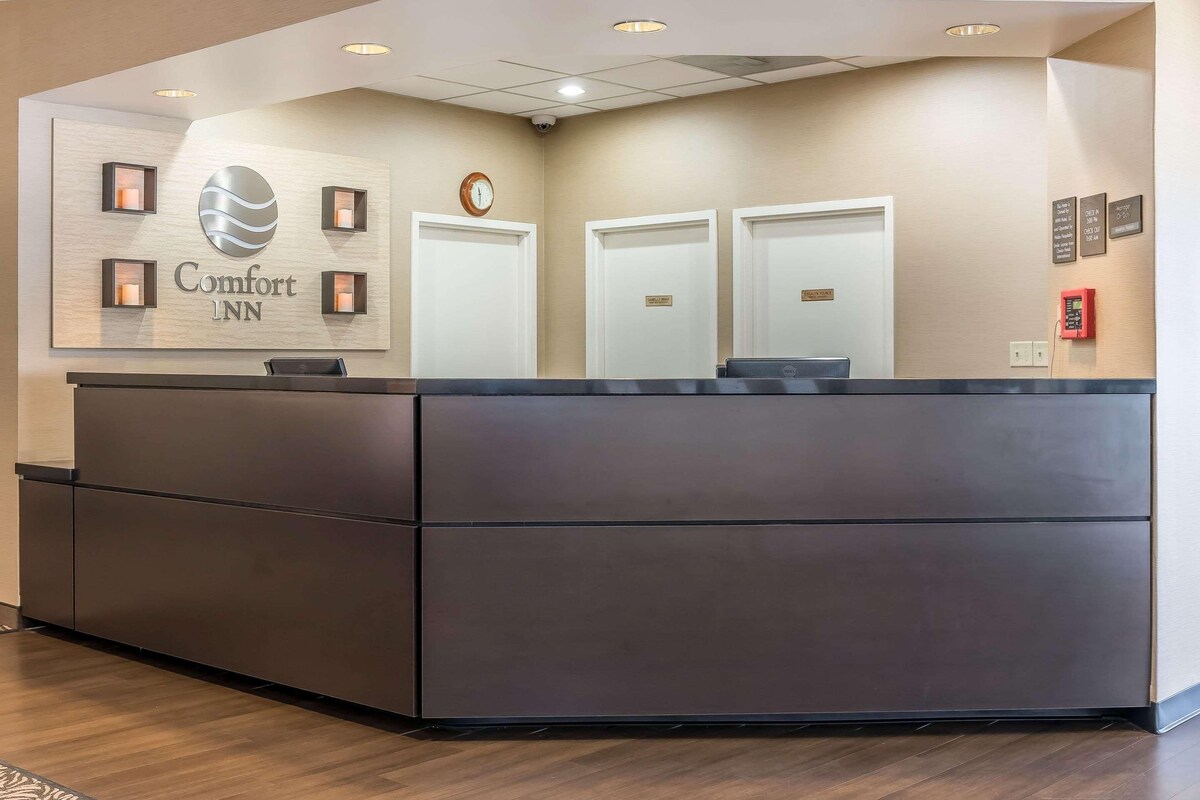 A reception desk with a sign reading "Comfort Inn" and three doors.