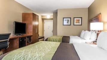 Une chambre d’hôtel avec deux lits, un bureau avec une télévision, un minibar et une porte donnant sur un couloir.
