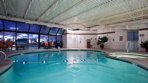 An indoor swimming pool with clear glass walls, a tiled floor, and a ceiling with metal beams. - Holiday Inn Express Mesa Verde-Cortez by IHG (Cortez)