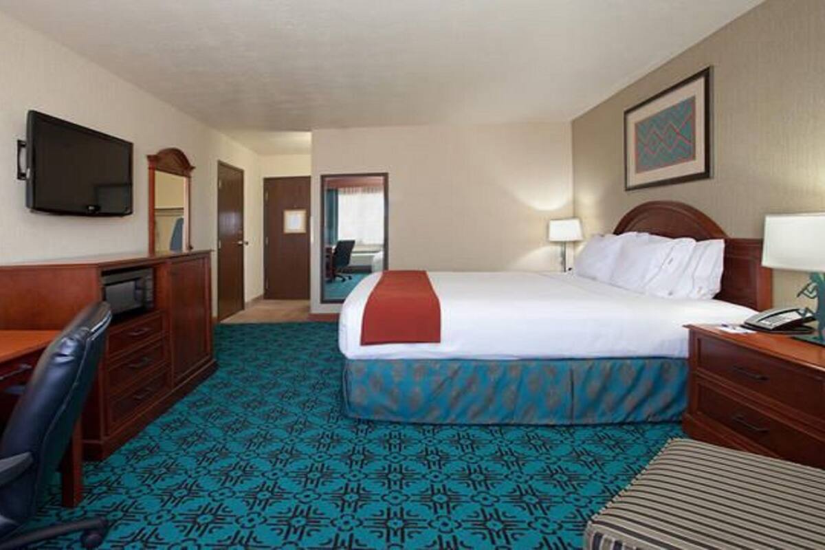 Une chambre d’hôtel équipée d’un lit, d’un bureau, d’une chaise et d’un téléviseur.