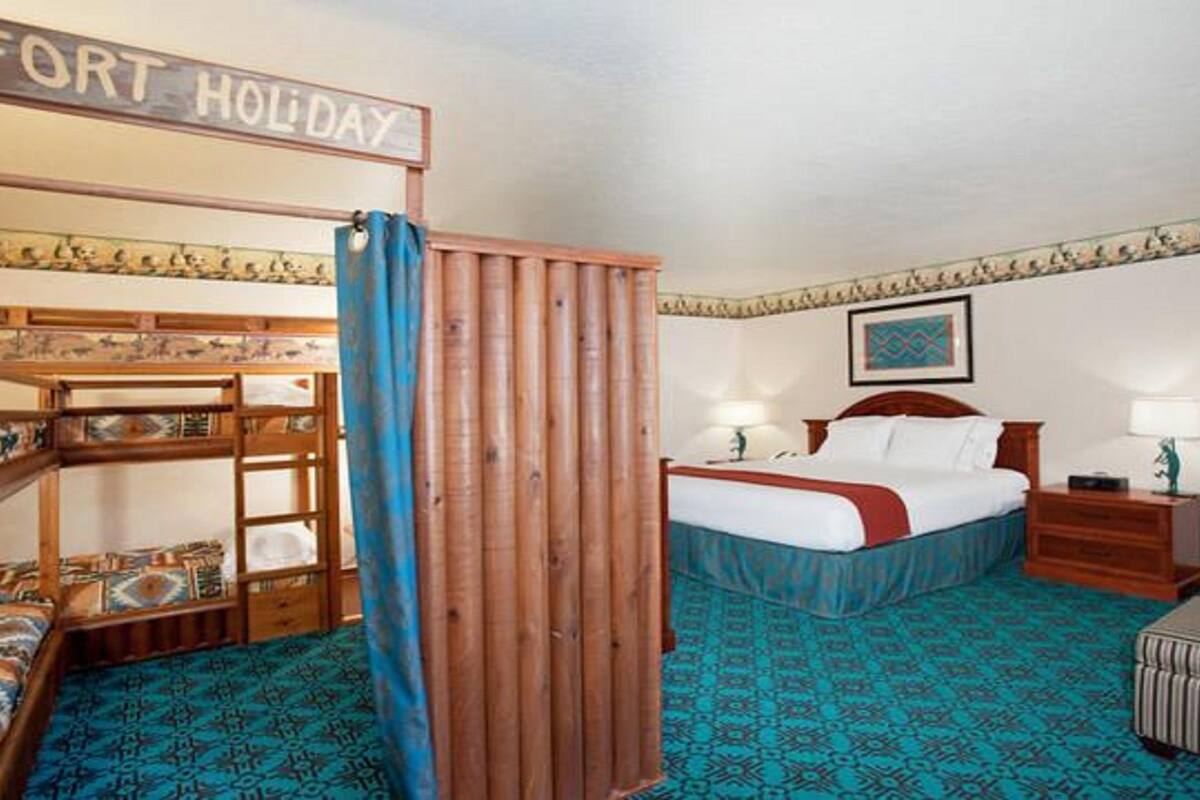 Une chambre avec des lits superposés, un lit, une table de chevet, une lampe et une pancarte sur laquelle on peut lire « FORT HOLIDAY ».