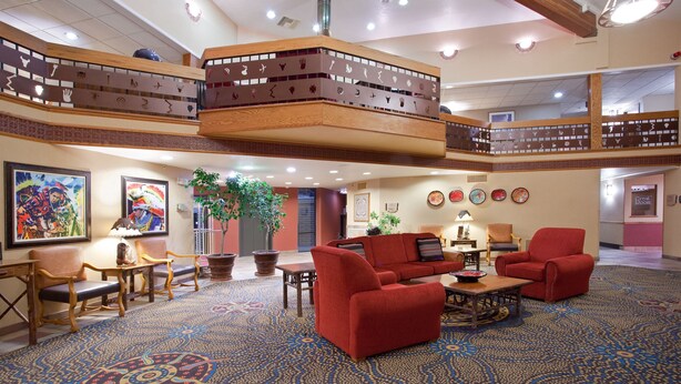 A spacious lobby with a high ceiling, a central seating area with red sofas, a patterned carpet, and a balcony with wooden railings. - Holiday Inn Express Mesa Verde-Cortez by IHG (Cortez)