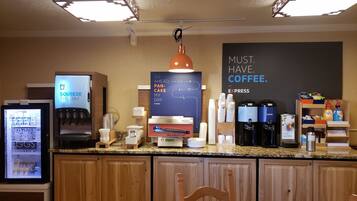 Un comptoir de petit-déjeuner équipé d’une machine à café, d’un réfrigérateur rempli de produits frais et d’un panneau indiquant : « UN CAFÉ, C’EST INDISPENSABLE ».