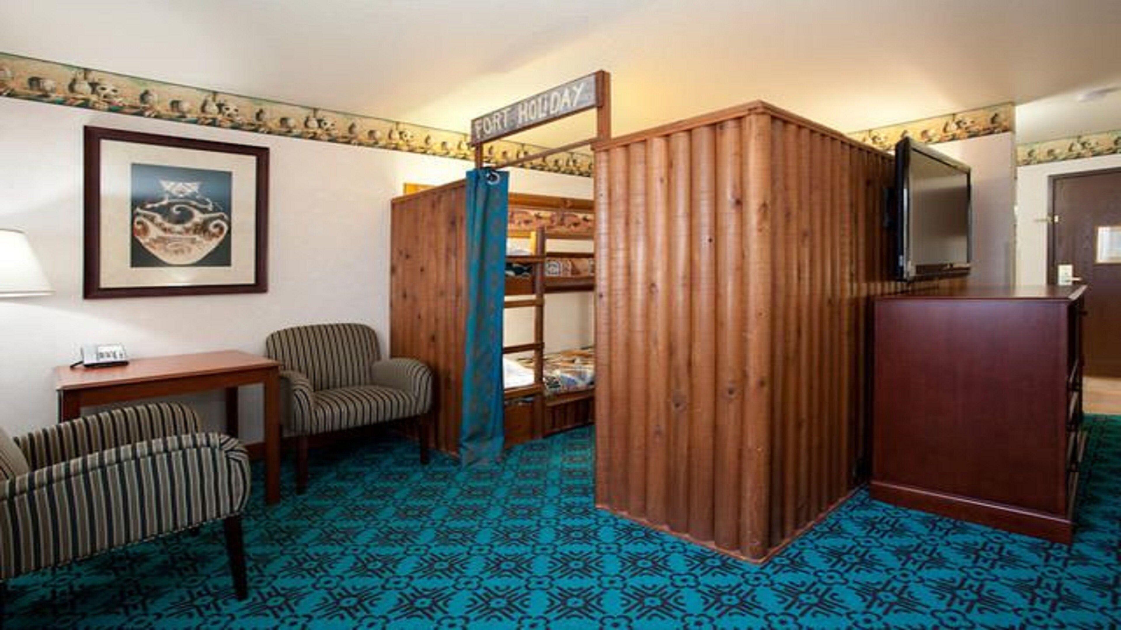 Una habitación con literas, un escritorio, una silla, un televisor y un cuadro en la pared.