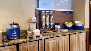 A breakfast bar with a 'Good Morning' sign, a 'Feelin' Fresh This Morning?' sign, and a 'Fruit' sign. There are containers of oatmeal, milk, and juice, as well as bowls of fruit. - Holiday Inn Express Mesa Verde-Cortez by IHG (Cortez)
