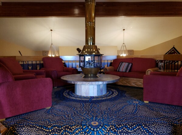 A cozy lounge area with a central round table, red sofas, and a patterned carpet. - Holiday Inn Express Mesa Verde-Cortez by IHG (Cortez)