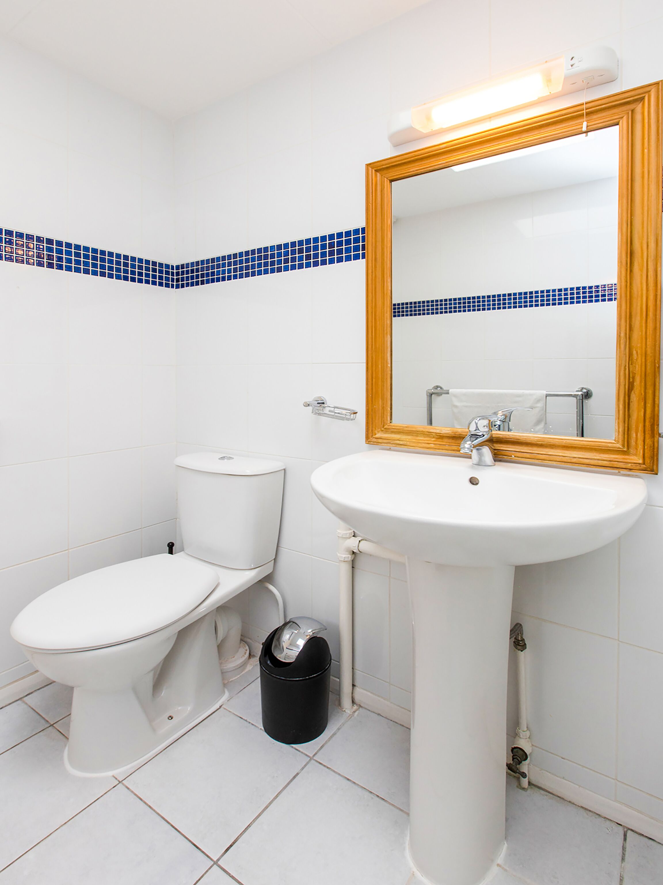 Une salle de bain avec des toilettes, un lavabo et un miroir.
