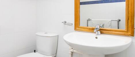 Une salle de bain avec des toilettes, un lavabo et un miroir.